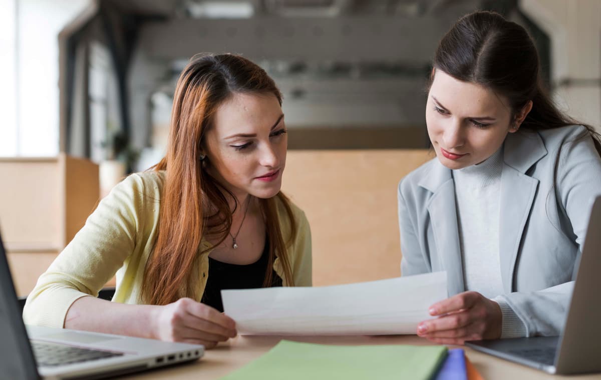 two-young-businesswoman-looking-paper-office